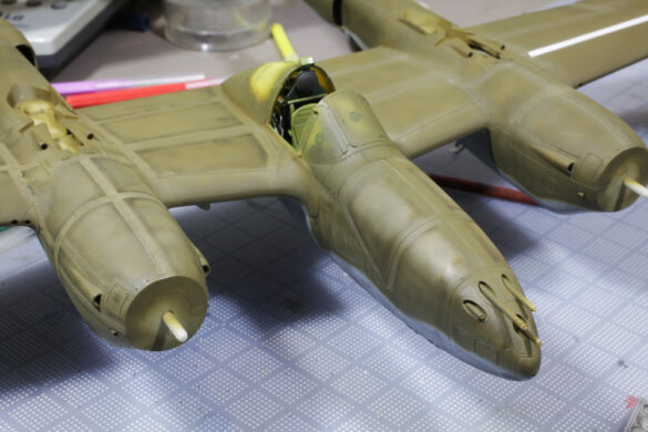 Photo Gallery – Tamiya 1/48 P-38G Lightning by Chris Wauchop Radio compartment detailing using 0.2 mm and 0.3 mm wire – painted placards and realistic wiring. Supercharger units finished with layered metallic and brown/black shades for realistic depth. Fuselage underside showing grime wash and added hydraulic brake lines. Drop tanks weathered for operational realism, mounted underwing. Panel line seal tape simulation using airbrush fading and masking techniques. Camouflage tones stippled for realistic weathered surface finish. Paint wear and black exhaust marks enhance visual realism. Cockpit close-up with foil-made harness and mirror wire control. Wing underside shows soot, staining, and sealing tape simulation. Tail surfaces display extensive weathering and exhaust wear effects.