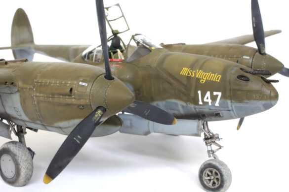 Photo Gallery – Tamiya 1/48 P-38G Lightning by Chris Wauchop Radio compartment detailing using 0.2 mm and 0.3 mm wire – painted placards and realistic wiring. Supercharger units finished with layered metallic and brown/black shades for realistic depth. Fuselage underside showing grime wash and added hydraulic brake lines. Drop tanks weathered for operational realism, mounted underwing. Panel line seal tape simulation using airbrush fading and masking techniques. Camouflage tones stippled for realistic weathered surface finish. Paint wear and black exhaust marks enhance visual realism. Cockpit close-up with foil-made harness and mirror wire control. Wing underside shows soot, staining, and sealing tape simulation. Tail surfaces display extensive weathering and exhaust wear effects.