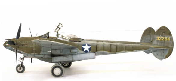 Photo Gallery – Tamiya 1/48 P-38G Lightning by Chris Wauchop Radio compartment detailing using 0.2 mm and 0.3 mm wire – painted placards and realistic wiring. Supercharger units finished with layered metallic and brown/black shades for realistic depth. Fuselage underside showing grime wash and added hydraulic brake lines. Drop tanks weathered for operational realism, mounted underwing. Panel line seal tape simulation using airbrush fading and masking techniques. Camouflage tones stippled for realistic weathered surface finish. Paint wear and black exhaust marks enhance visual realism. Cockpit close-up with foil-made harness and mirror wire control. Wing underside shows soot, staining, and sealing tape simulation. Tail surfaces display extensive weathering and exhaust wear effects.