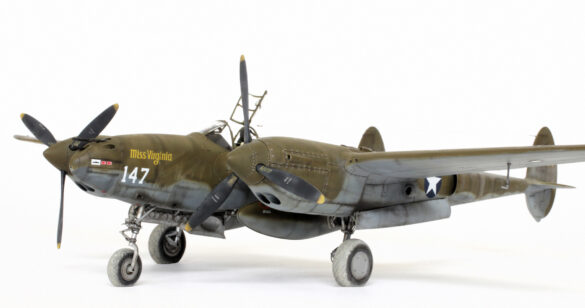 Photo Gallery – Tamiya 1/48 P-38G Lightning by Chris Wauchop Radio compartment detailing using 0.2 mm and 0.3 mm wire – painted placards and realistic wiring. Supercharger units finished with layered metallic and brown/black shades for realistic depth. Fuselage underside showing grime wash and added hydraulic brake lines. Drop tanks weathered for operational realism, mounted underwing. Panel line seal tape simulation using airbrush fading and masking techniques. Camouflage tones stippled for realistic weathered surface finish. Paint wear and black exhaust marks enhance visual realism. Cockpit close-up with foil-made harness and mirror wire control. Wing underside shows soot, staining, and sealing tape simulation. Tail surfaces display extensive weathering and exhaust wear effects.