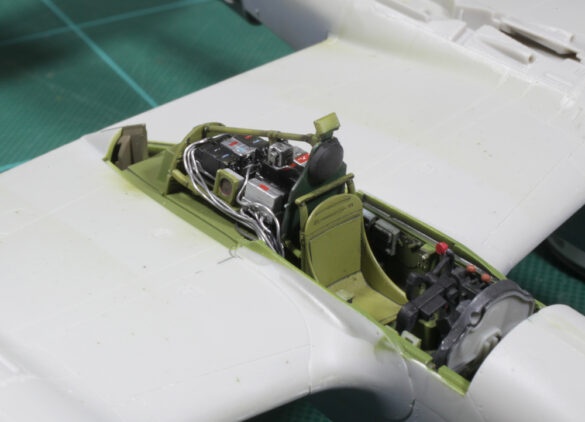 Photo Gallery – Tamiya 1/48 P-38G Lightning by Chris Wauchop Radio compartment detailing using 0.2 mm and 0.3 mm wire – painted placards and realistic wiring. Supercharger units finished with layered metallic and brown/black shades for realistic depth. Fuselage underside showing grime wash and added hydraulic brake lines. Drop tanks weathered for operational realism, mounted underwing. Panel line seal tape simulation using airbrush fading and masking techniques. Camouflage tones stippled for realistic weathered surface finish. Paint wear and black exhaust marks enhance visual realism. Cockpit close-up with foil-made harness and mirror wire control. Wing underside shows soot, staining, and sealing tape simulation. Tail surfaces display extensive weathering and exhaust wear effects.