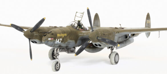 Photo Gallery – Tamiya 1/48 P-38G Lightning by Chris Wauchop Radio compartment detailing using 0.2 mm and 0.3 mm wire – painted placards and realistic wiring. Supercharger units finished with layered metallic and brown/black shades for realistic depth. Fuselage underside showing grime wash and added hydraulic brake lines. Drop tanks weathered for operational realism, mounted underwing. Panel line seal tape simulation using airbrush fading and masking techniques. Camouflage tones stippled for realistic weathered surface finish. Paint wear and black exhaust marks enhance visual realism. Cockpit close-up with foil-made harness and mirror wire control. Wing underside shows soot, staining, and sealing tape simulation. Tail surfaces display extensive weathering and exhaust wear effects.