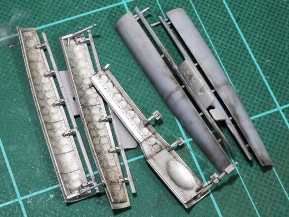 Photo Gallery – Tamiya 1/48 P-38G Lightning by Chris Wauchop Radio compartment detailing using 0.2 mm and 0.3 mm wire – painted placards and realistic wiring. Supercharger units finished with layered metallic and brown/black shades for realistic depth. Fuselage underside showing grime wash and added hydraulic brake lines. Drop tanks weathered for operational realism, mounted underwing. Panel line seal tape simulation using airbrush fading and masking techniques. Camouflage tones stippled for realistic weathered surface finish. Paint wear and black exhaust marks enhance visual realism. Cockpit close-up with foil-made harness and mirror wire control. Wing underside shows soot, staining, and sealing tape simulation. Tail surfaces display extensive weathering and exhaust wear effects.