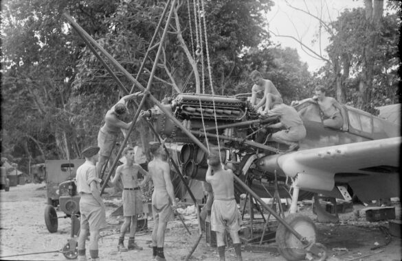 "1/48 scale Pacific airfield diorama with PSP and fuel truck" alt="US WW2 bomb cart and drums beside F4U Corsair" alt="Ground crew and maintenance scene on jungle runway" alt="Diorama showing GMC fuel bowser and PSP strip" alt="Scale model US bomb hoist in tropical airfield setting"