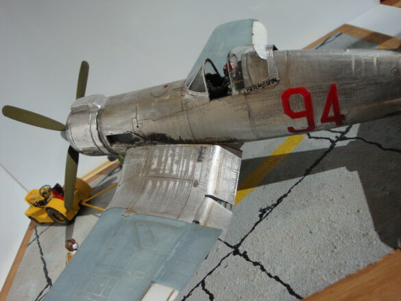 FG-1D Corsair #94-“Big Hummer” at Reno 1971 / Pilot ~ Bob Mitchem. FG-1D Corsair “Big Hammer” – 1/48 model with aluminum foil skin, four-blade prop, Hasegawa carrier crew figures, and scratch-built diorama base, depicting a Reno 1971 scene.
